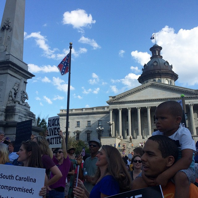 A rally at the South Carolina Statehouse for the removal of the Confederate flag, with the banner flying in the background. (photo by @maracgay/Instagram)