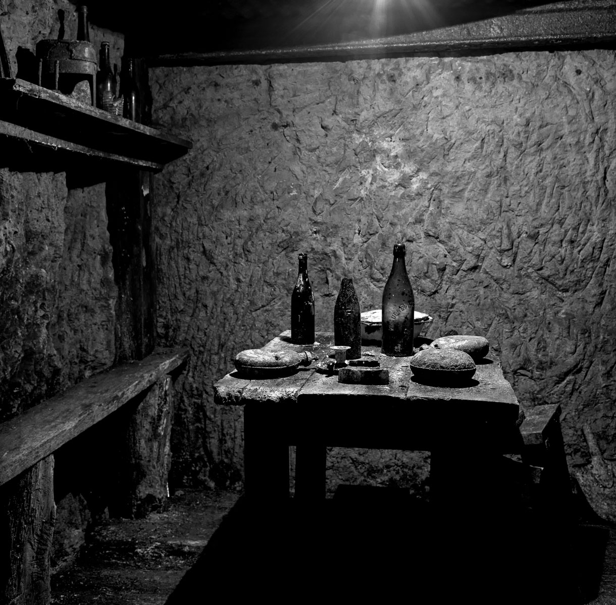 French soldiers' dining area underground with wine bottles, canteens and a serving dish. Photographed 6 December 2011. Vauquois, France. Terms of Use: These photos are for one-time use before January 1, 2015, limited to professional media outlets and blogs, in connection with an accompanying story about Jeffrey Gusky, his work and WWI-related discoveries. Stories appearing during the license period may be archived online by the media outlet or blog who published the story. This image is a low resolution version of the original. Higher resolution images are available by special arrangement with the artist. This image may not be modified and may not be used commercially except with a commercial license. This image is not available under any Creative Commons license. Copyright (c) 2011, Jeffrey Gusky. All Rights Reserved. Jeffrey Gusky, c/o attorney at P.O. Box 2526, Addison, TX 75001-2526. photos@jeffgusky.com .