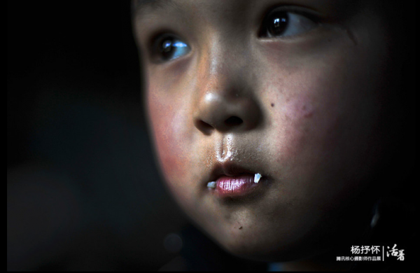 Grains of rice hang on the lips of a child benefitting from the free lunch program, an effort organized by journalists and promoted using Sina Weibo. Image via qq.com.