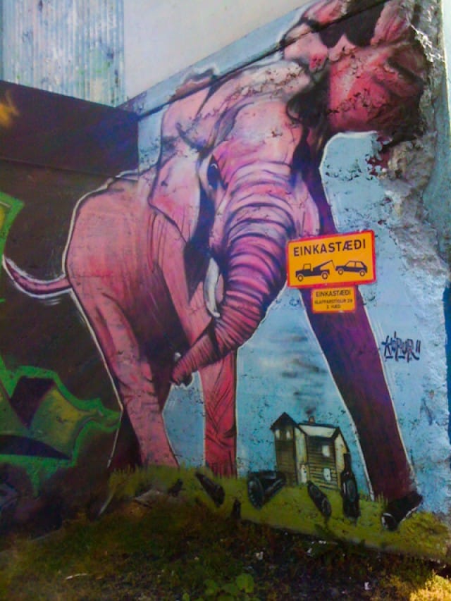 A fierce looking elephant in a parking lot.