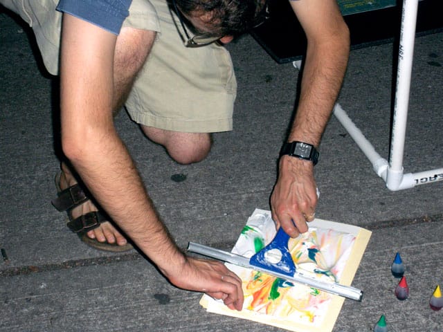 Ben McKelahan revealing a print made with his interactive "Drawing Machine"