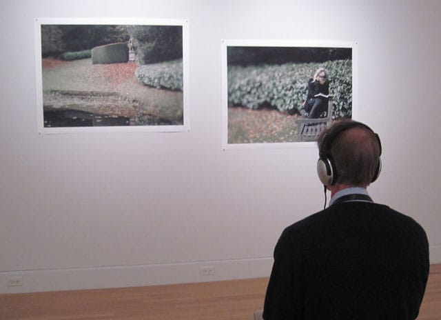 A viewer listening to the sound piece for "Laying Down Paths"