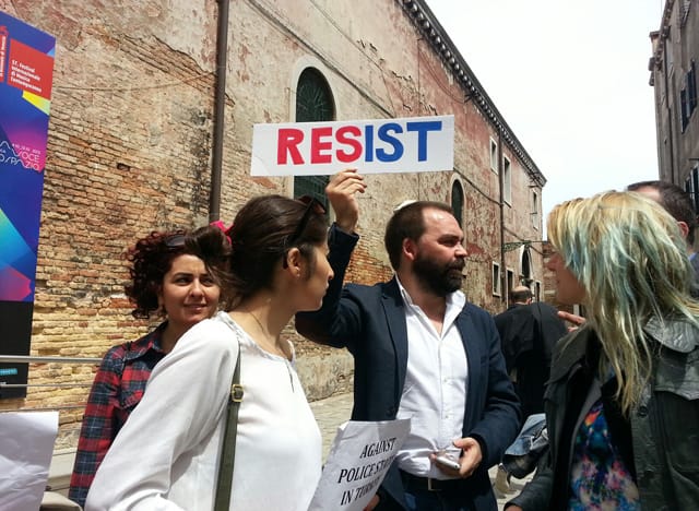 Artist ???? holds a "Resist" sign during today's protest at the Venice Biennale. (photo courtesy Defne Ayas)