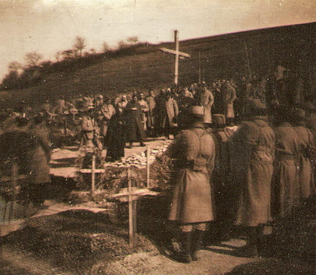 Soldiers gather around a priest at what seems to be a funeral.