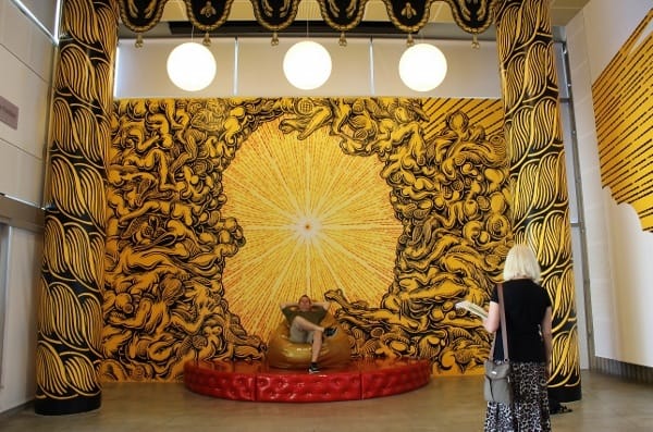 Mark Dean Veca’s installation “Pete’s Place” is inspired by Bernini’s Cathedra Petri in Rome, complete with Truck Nutz fringe. Here, the artist is seen giving visitors a lesson on how to sit in a papal-style throne.