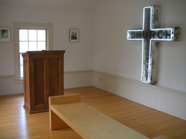 A room in the back displays the original cross — fittingly bordered in neon — and other artifacts from the church.