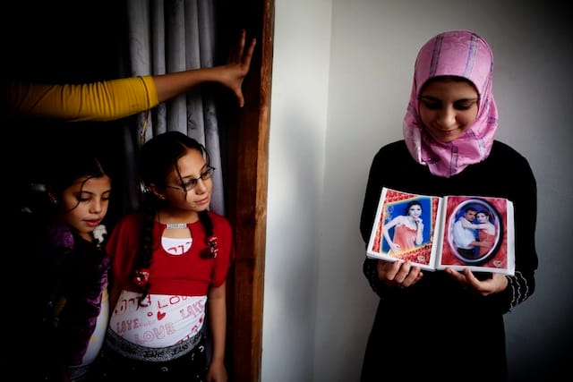 Tanya Habjouqa, from the series "Women of Gaza." Text for the photograph: "In the Gaza City home of Dr Jamal Shareef, a literature professor at Al Azhar University, his 16-year-old niece (R) shows pictures of her fiancé."
