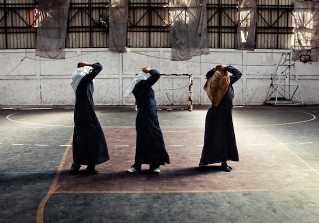 Tanya Habjouqa, from the series "Women of Gaza." Caption: "Young women exercise in gym, part of the women's associations with strong religious connections becoming increasingly predominant across Gaza. With a crippled economy and government under siege--the women's associations are offering relief to the community where others cannot--including daycare, orphan assistance, teaching of crafts, beauty salons, and spaces to exercise. Though it is a religious organization, believing in segregation between unmarried men and women, they acknowledge the limited space for women to explore and be healthy. Fully dressed in traditional "jilbab" as they work out, the women say they are covering at gym, as they have no privacy in the pubic sphere due to limited economic options. They cannot afford private gyms and are tired of being cramped in the home."