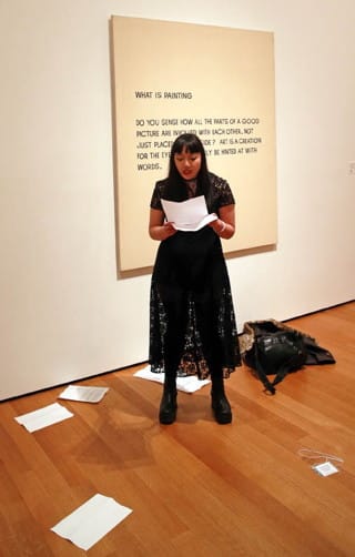 Trisha Low reads in front of John Baldessari's "What Is Painting" (1968) (click to enlarge)