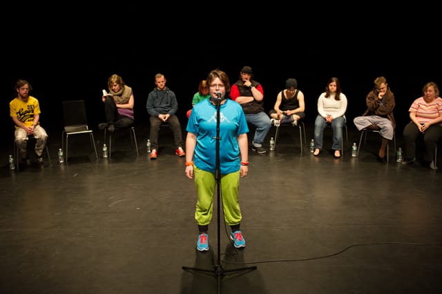 Performer Sara Hess stands at the microphone during a performance of Jerome Bel's Disabled Theater. (Photo: Ian Douglas; Courtesy: New York Live Arts)