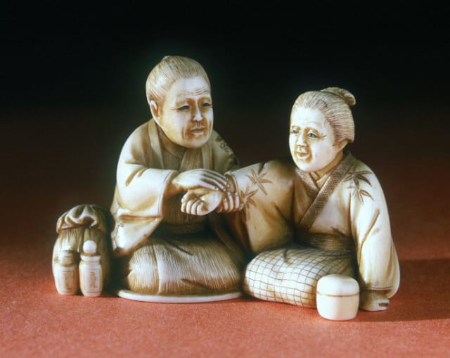 A 19th century ivory netsuke figure made by Chikaaki in Japan showing a doctor feeling the pulse of a patient