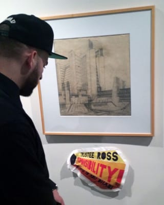 A museum visitor reading one of the G.U.L.F. graphics by a Futurist art work. (image by the author for Hyperallergic) (click to enlarge)