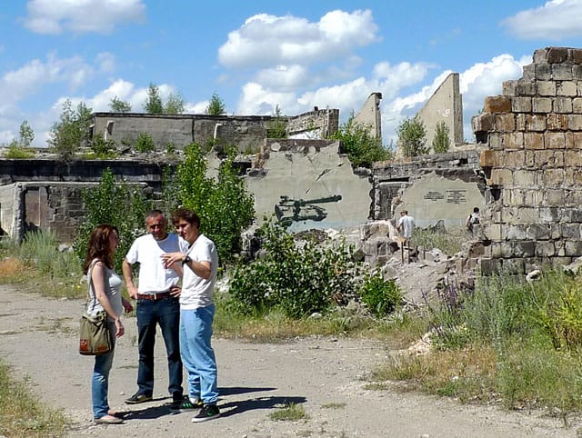 Members of Armenian group Artlab talking to Romanian artist Daniel Knorr, with Artlab's stencil of a Russian tank in the background (all photos by the author for Hyperallergic)