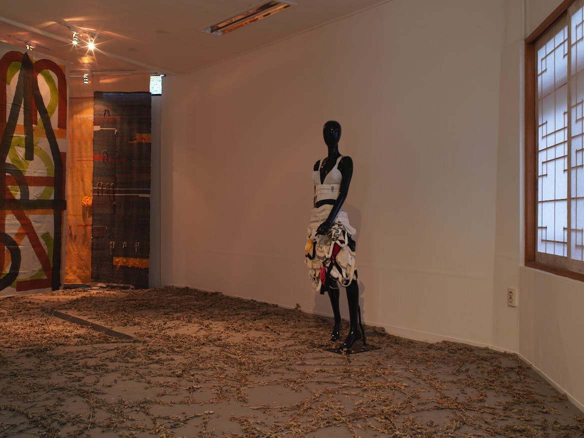 Left to right, one of eight sigil paintings by Elijah Burgher (2013-2014), “Jock Strap Dress” (2014) by K8 Hardy. “Window Dressing (Forest Cloaks)” (2014) by AA Bronson and Travis Meinolf is in the background.