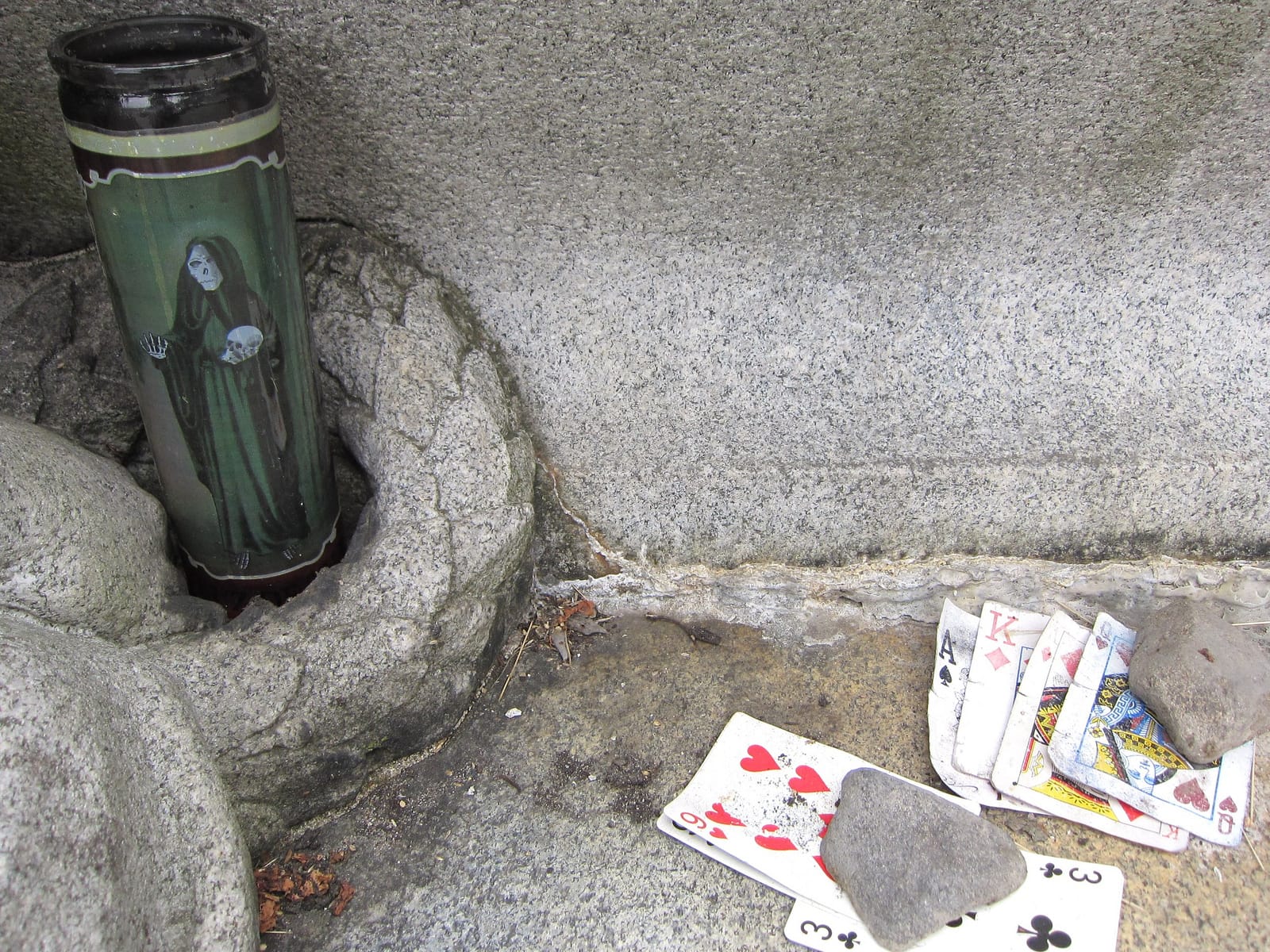 A Santa Muerte candle with playing cards at Houdini's grave