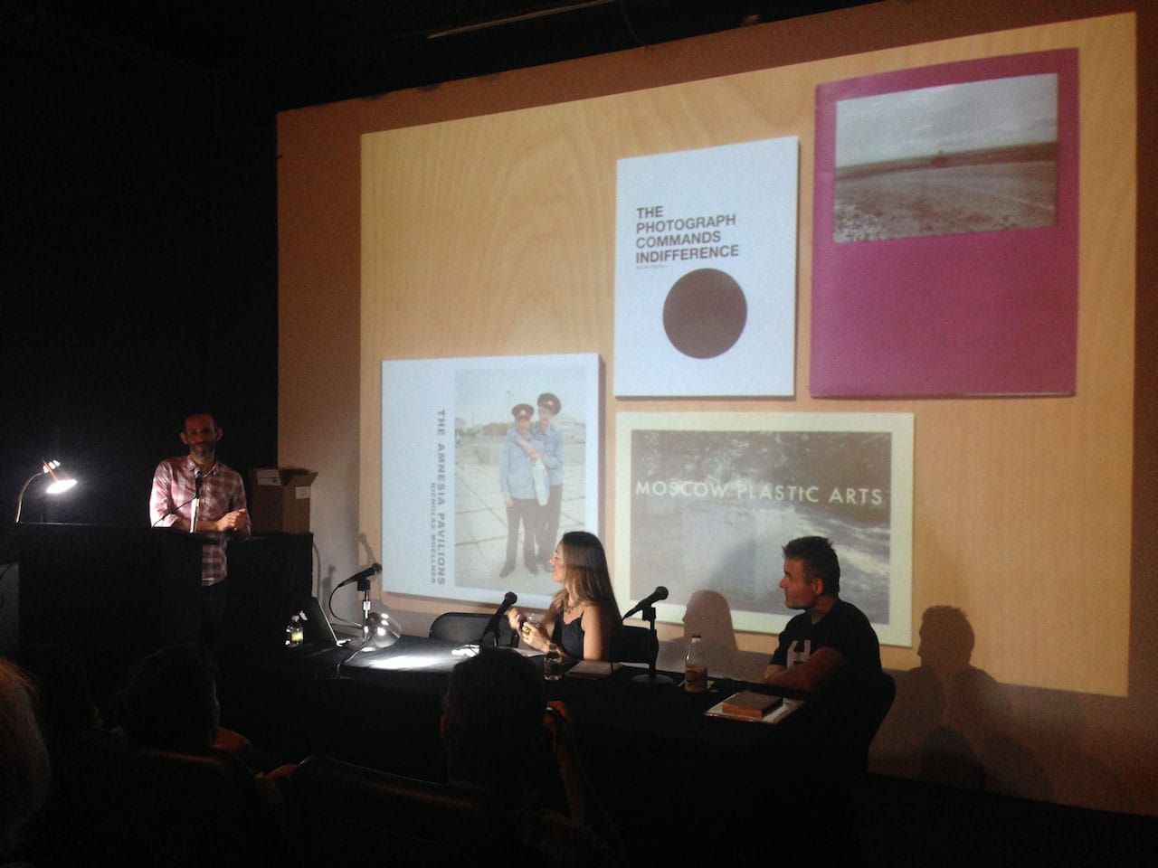The "Photo and Text" panel, with Nicholas Muellner at left, Russet Lederman in the middle, and Brad Zellar at right. On the projector are several of Muellner's books (from left): 'The Amnesia Pavillions' (A-Jump Books, Ithaca, NY, 2011), 'The Photograph Commands Indifference' (A-Jump Books, Ithaca, NY, 2009), 'Moscow Plastic Arts' (Arcadia University Art Gallery, Glenside, PA 2005), 'Mountain Shadow Place' (A-Jump Books, Ithaca, NY, 2012)