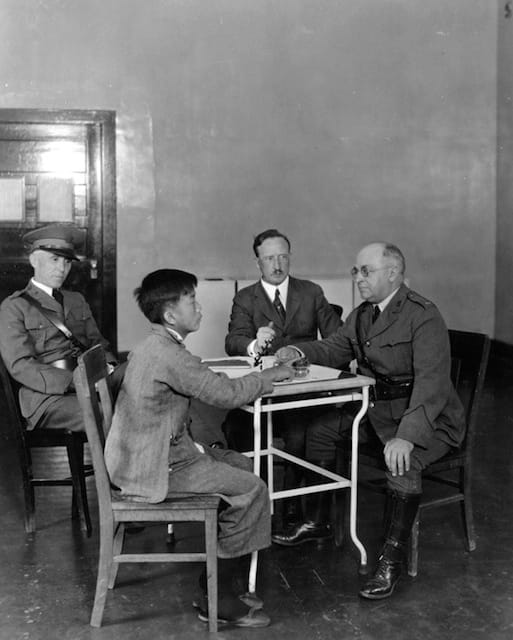 A Chinese immigrant is interrogated by US immigration inspectors on Angel Island, 1923. National Archives, College Park, MD (90-G-124-479).