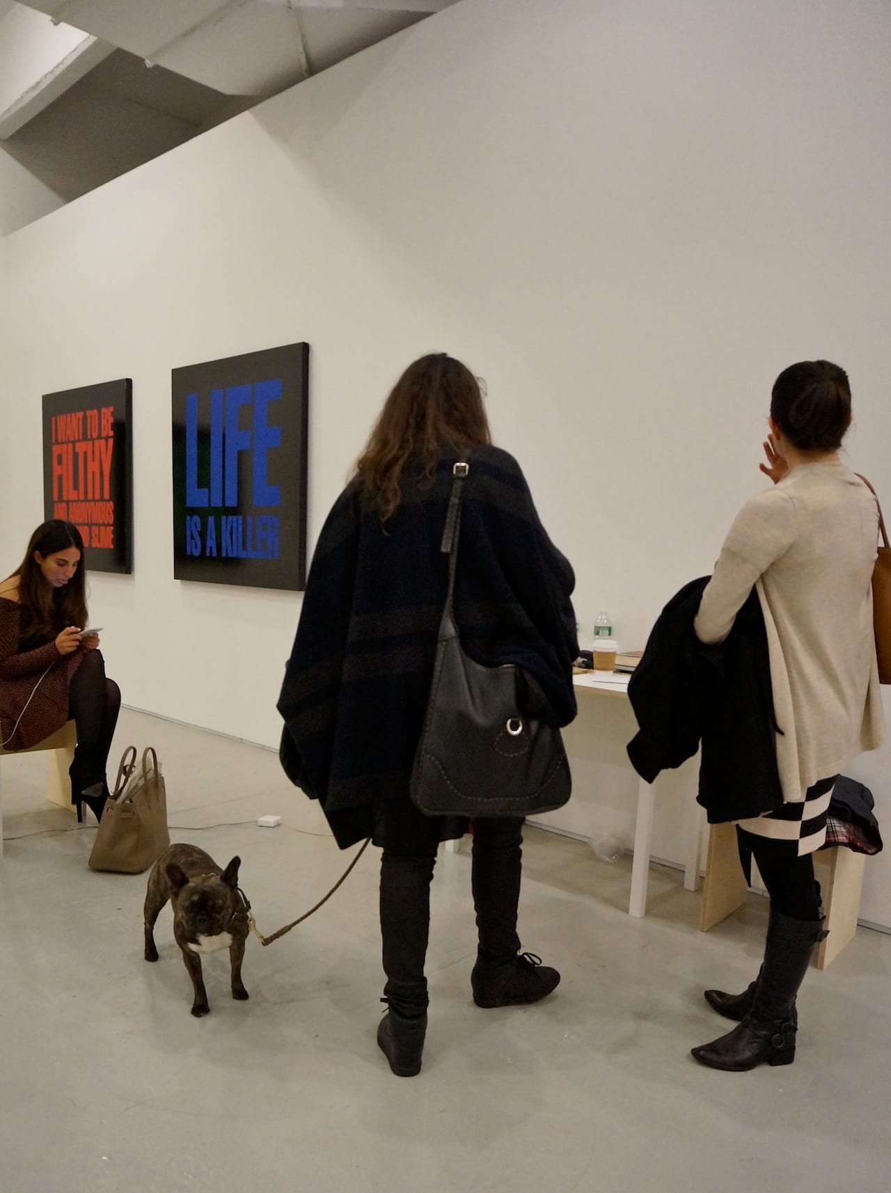 Women and dog visit the booth of Max Wigram Gallery, showing 1989 paintings by John Giorno