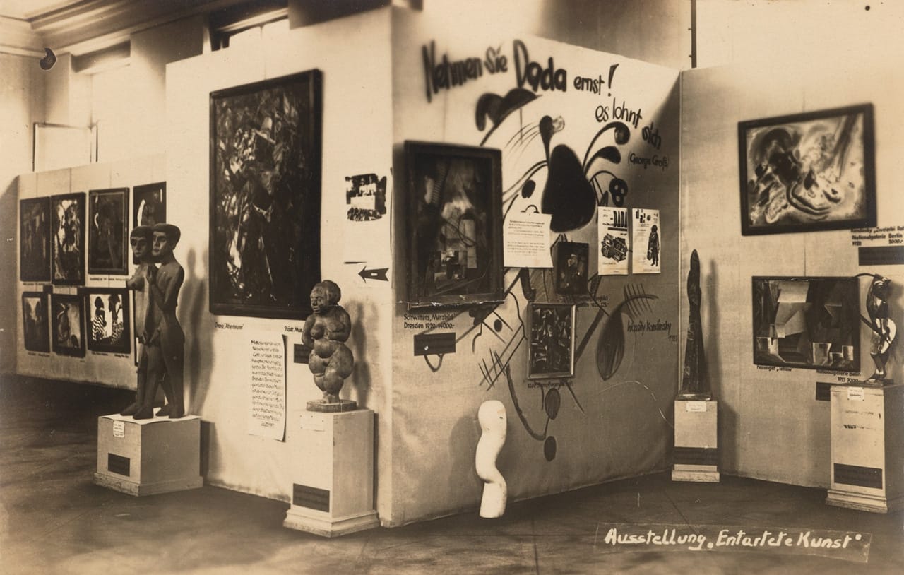 'Entarte Kunst' Berlin exhibition postcard, showing artworks and signage "Nehmen sie Dada Ernst"