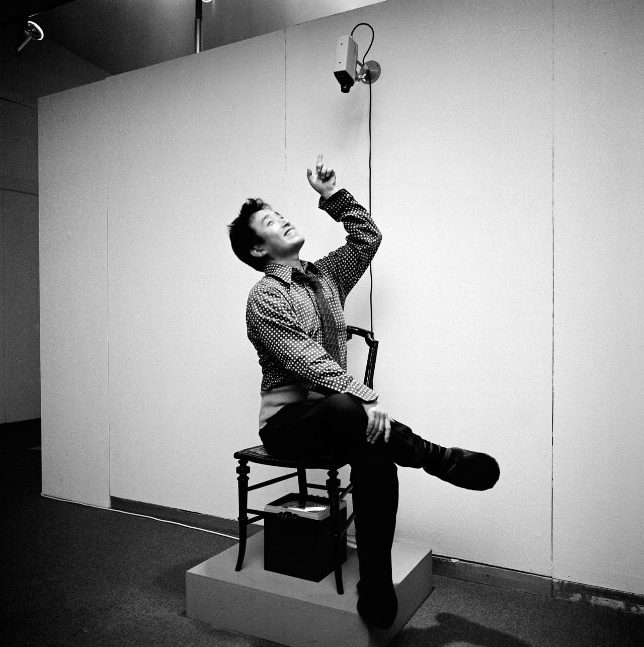 Nam June Paik sitting in "TV Chair" (1968/1976) in 'Nam June Paik Werke, 1946–1976: Music, Fluxus, Video,' 1976 (photo © Friedrich Rosenstiel, Cologne) (click to enlarge)