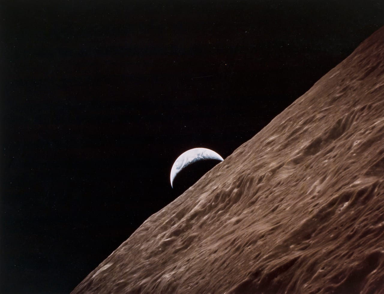 Ronald Evans The crescent Earth rising from behind the Moon, Apollo 17, December 1972 Large format vintage chromogenic print, 27 x 34.5cm, flush-mounted on original NASA card, [NASA  AS17-152-23274] Illustrated: A Man on the Moon, p.260 Est. £3,000-5,000 Reproduction, © Bloomsbury Auctions