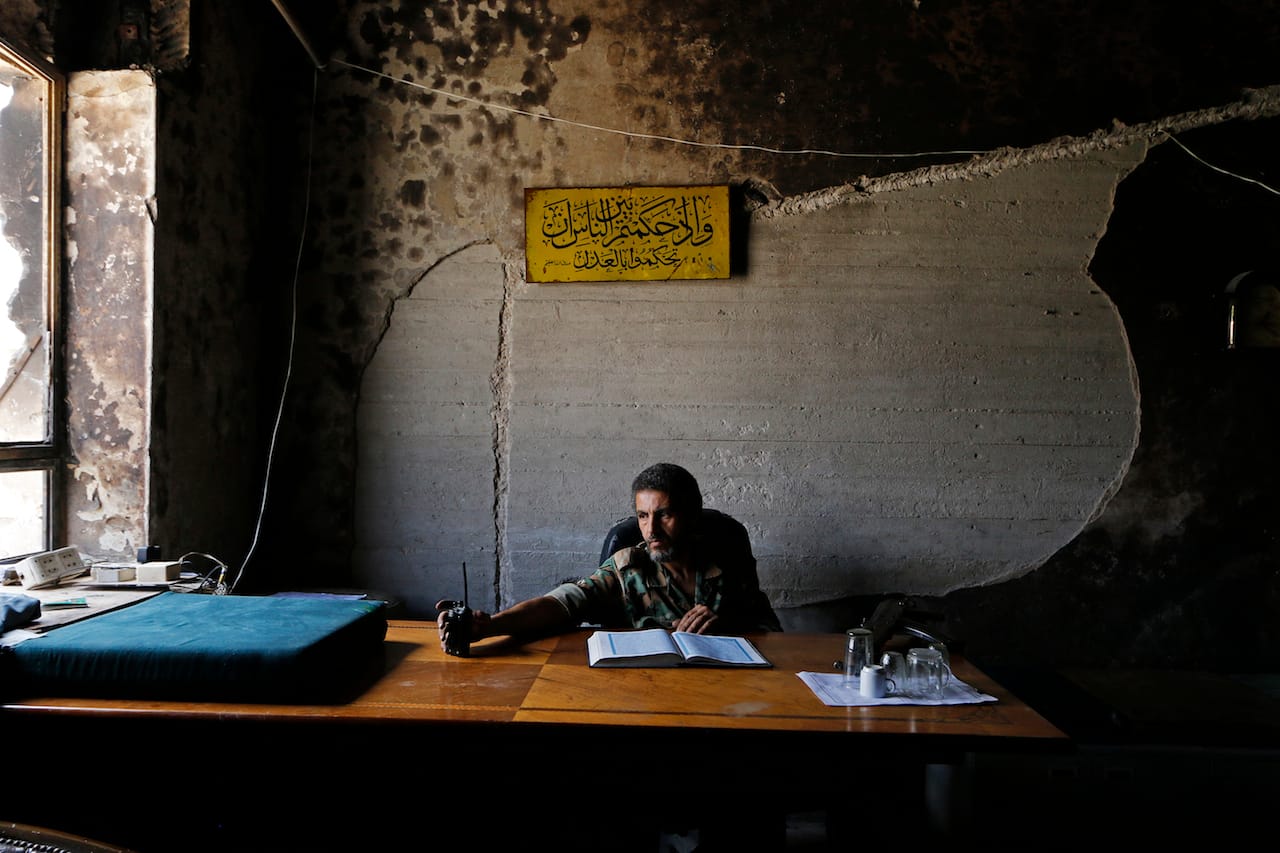 A Free Syrian Army fighter sits behind a desk in Palace of Justice in Aleppo, June 6, 2014. © Nour Kelze.