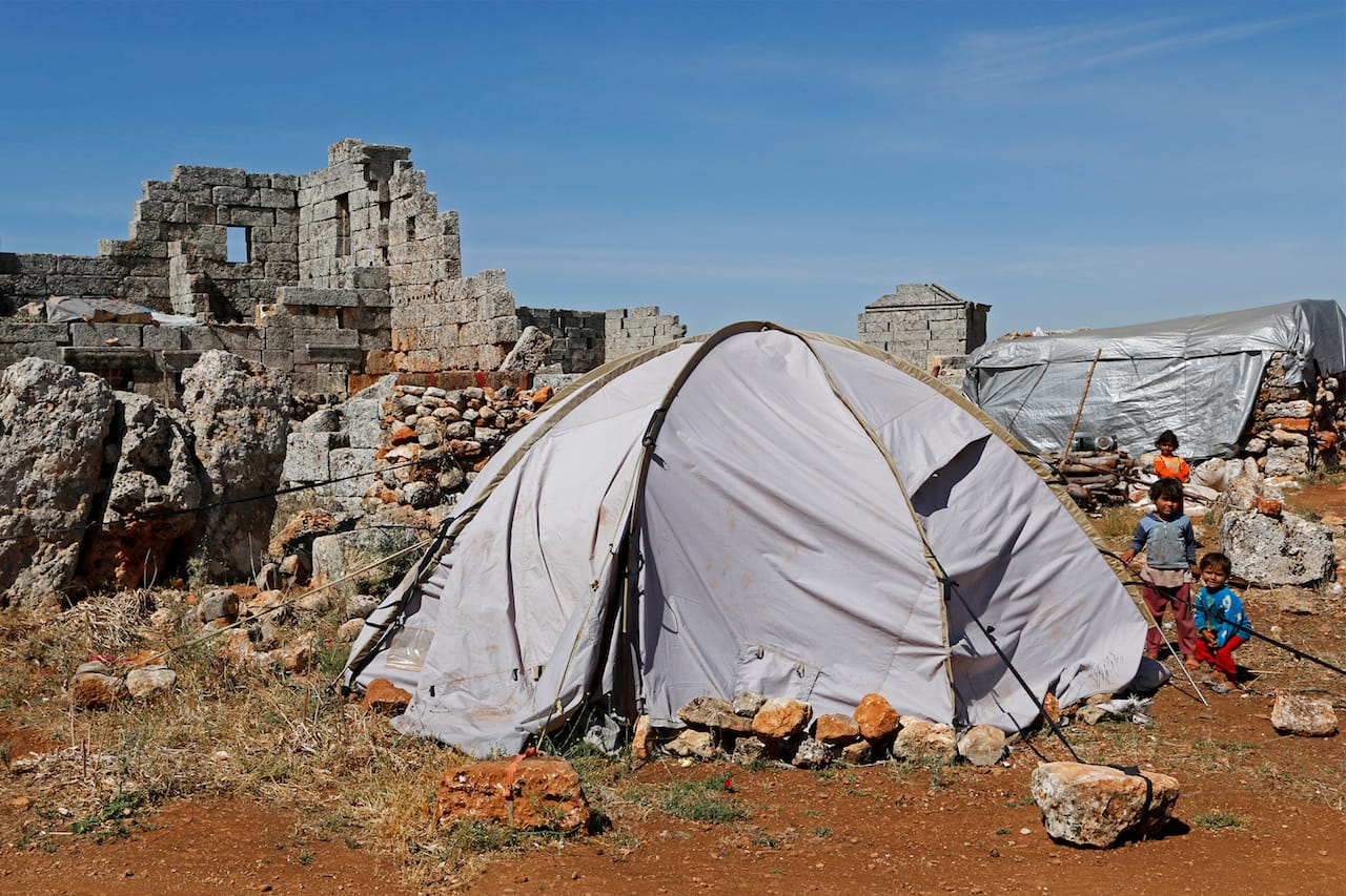 Children, who have been displaced due to the fighting between rebels and the forces of Syrian President Bashar al-Assad, sit beside a tent at the Shinshrah archaeological site, in the Idlib countryside. Many Syrians living close to the frontline fled to live at the Shinshrah archaeological site about two years ago, activists said. The site now contains a school, a mosque and recently the community was digging a water well. May 18, 2014. © Nour Kelze.
