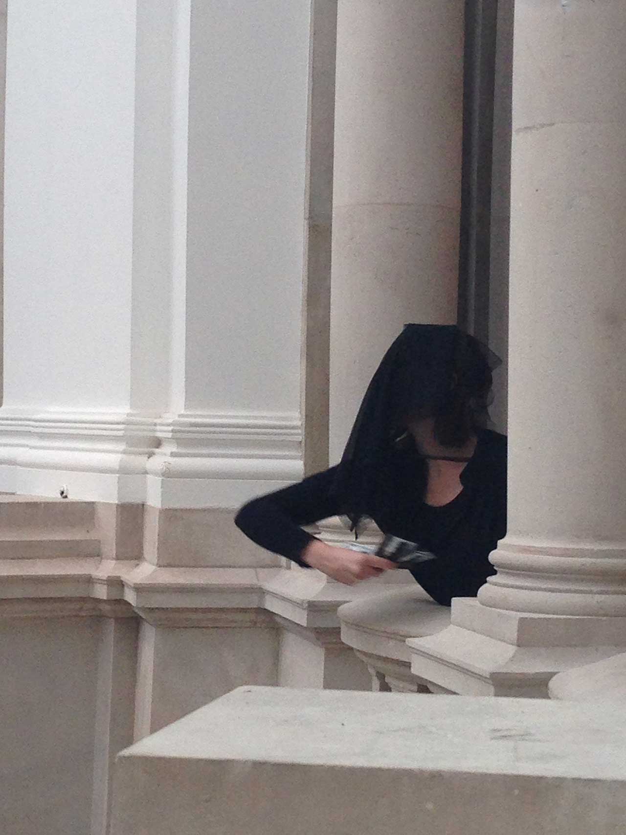 A veiled Liberate Tate member throwing money