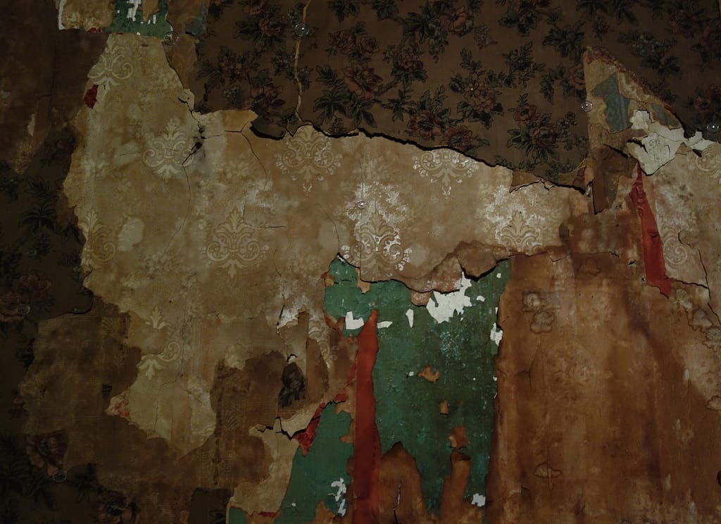 An unrestored wall where layers of wallpaper have peeled away