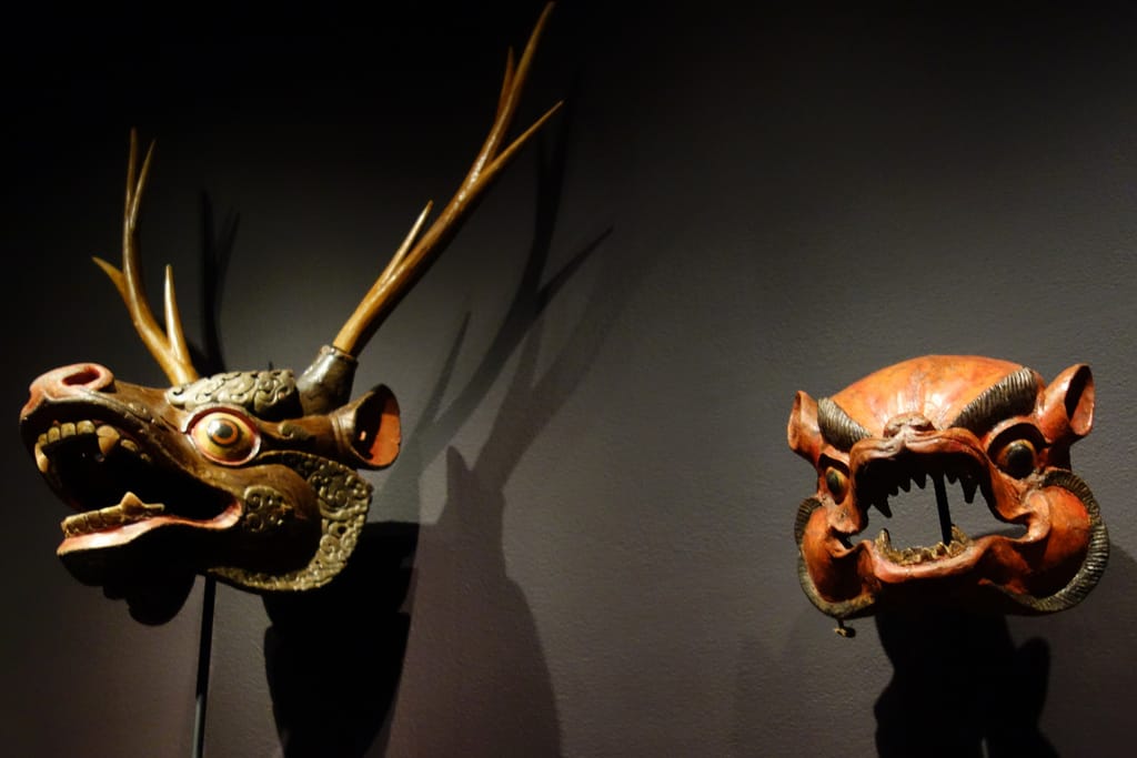 At left: deer mask from Bhutan (20th century), papier-mâché, polychrome; at right: wild animal mask from Bhutan (19th century), papier-mâché, polychrome