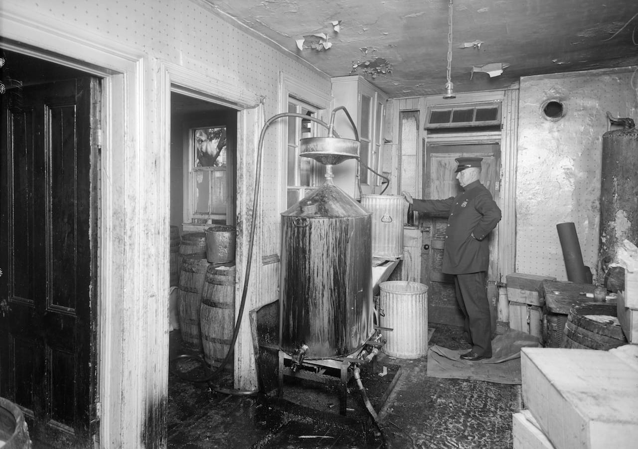A police officer inspecting stills for bootleg liquor in Brooklyn (July 1927) (courtesy New York City Municipal Archives)
