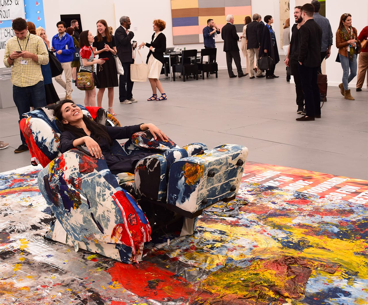 A fairgoer reclining in one of Korakrit Arunanondchai's "denim massage chairs (growing up together)" (2015), a Frieze Project