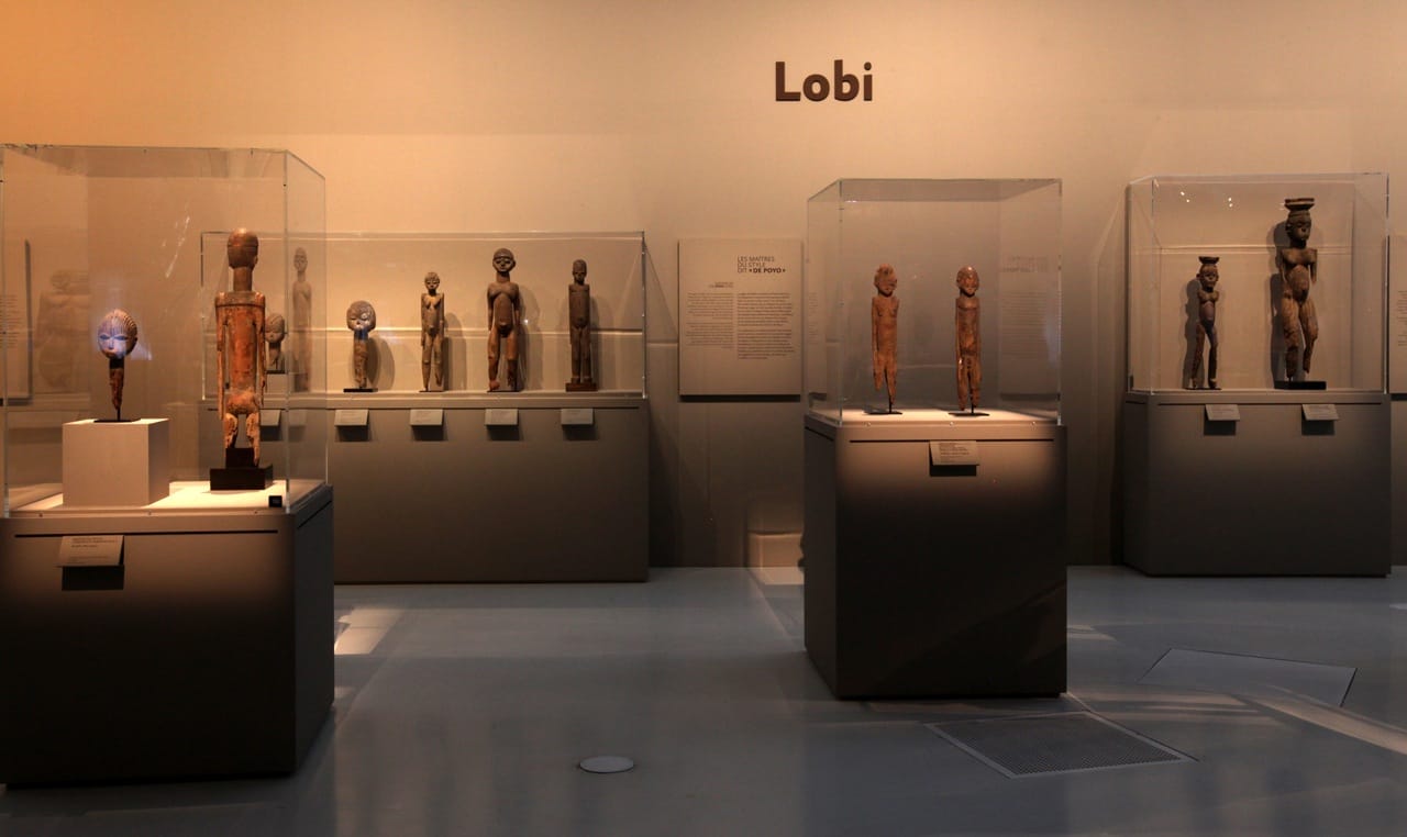 MusÈe du quai Branly. Affiche de l'exposition "Les maÓtres de la sculpture de CÙte d'Ivoire". Du 14 avril au 26 juillet 2015. Galerie Jardin.  Vue de l'exposition. RÈunissant prËs de 200 oeuvres historiques et contemporaines, l'exposition met ‡ l'honneur les grands sculpteurs et les Ècoles de sculpture de CÙte d'Ivoire et de ses pays limitrophes. Elle resitue les sculptures dans le contexte religieux et stylistique des Ateliers du 19e et dÈbut du 20e siËcle, notamment chez les SÈnoufo, les Lobi, les Dan ou encore les BaoulÈ, en les considÈrant sous l'angle de leur force esthÈtique et de la singularitÈ de leur crÈateur. L'exposition prÈsente Ègalement des installations et oeuvres d'artistes contemporains: la nouvelle gÈnÈration d'artistes africains ´ transnationaux ª, hÈritiËre des grands artistes du passÈ, met en avant la continuitÈ crÈative des sculpteurs d'Afrique de l'Ouest dans la pÈriode postcoloniale.