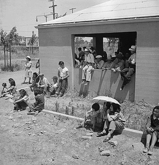 Stockton, CA, May 19, 1943. Watching the buses arrive with new incarcerees, Stockton Assembly Center (Photographed by Dorothea Lange, WRA / Courtesy of the National Archives and Records Administration (National Archives Identifier 537730))