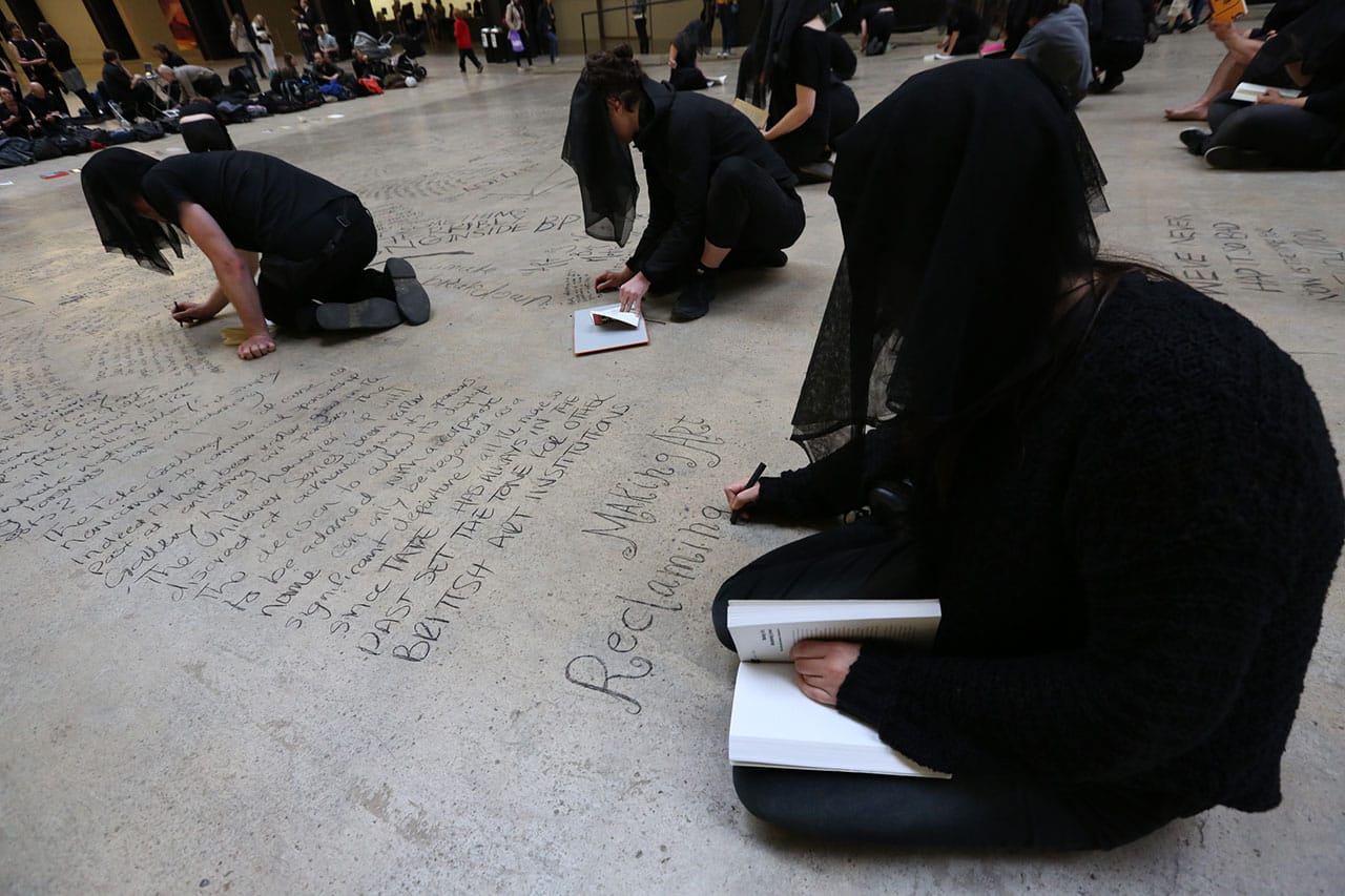Performers writing on the floor of the museum