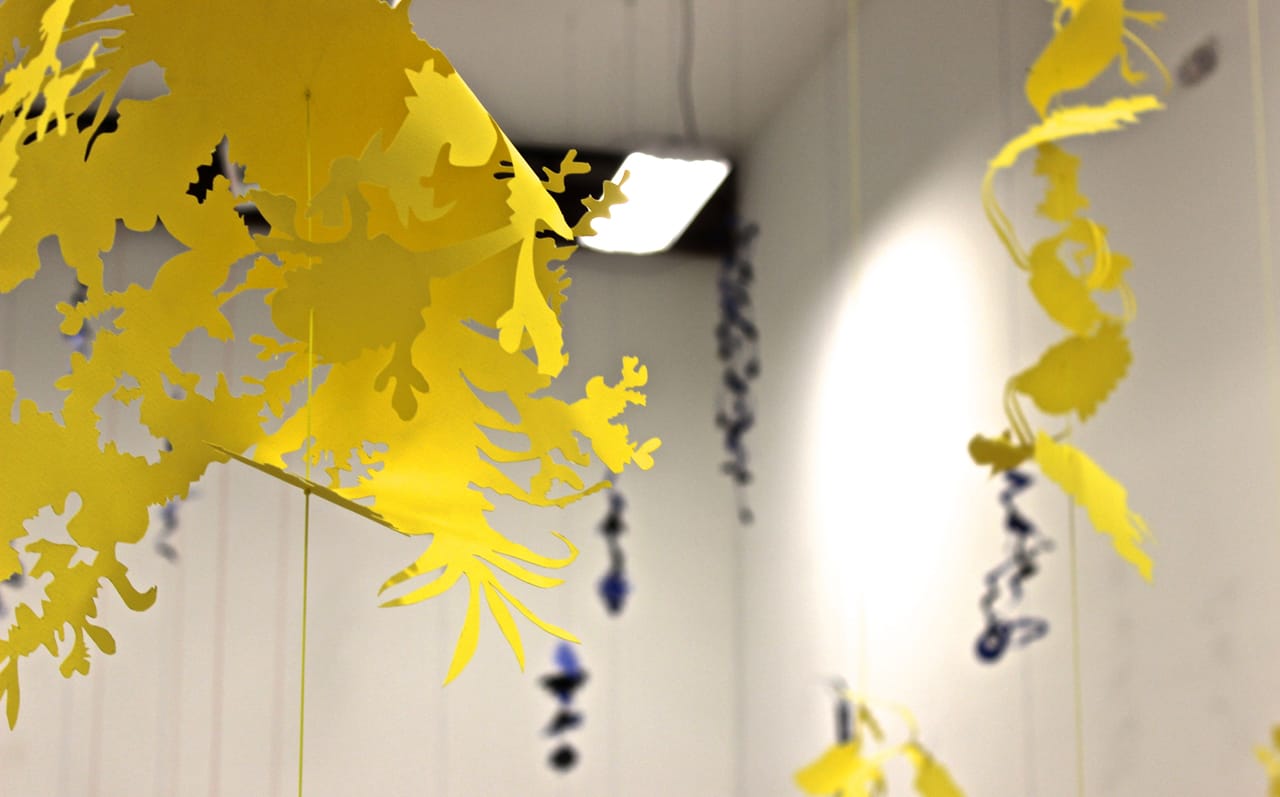 The paper cut shapes hanging from "Tensions (yellow)" (foreground) and "Tensions (blue)" (background).
