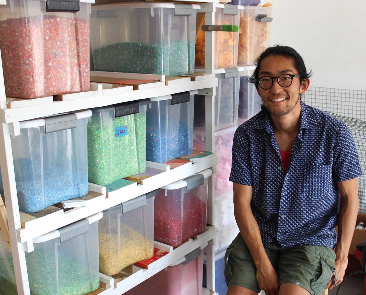 Eiji Jimbo, sitting beside bins of shredded and sorted HDPE