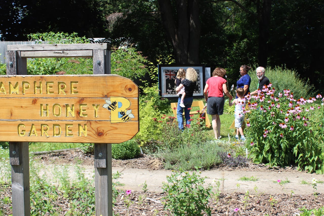 Community members examine the newly installed Fante Asafo flag at the Lamphere Honey Garden