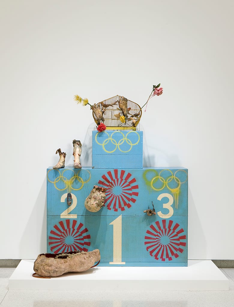Tetsumi Kudō, "Olympic Winners Platform (Pollution Olympics - Pollution Game - L'art pressentiment)" 1970–72), painted wood, pegboard, cotton, plastic, polyester, painted cage, artificial flowers, toy (Walker Art Center, Minneapolis T. B. Walker Acquisition Fund, 2008; © Artists Rights Society/ARS, New York / ADAGP, Paris)