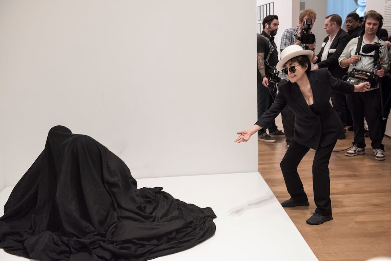 Yoko Ono interacting with people activating Bag Piece (1964), a participatory work in Yoko Ono: One Woman Show, 1960-1971, on view at MoMA, May 17 -September 7, 2015. Photo by Ryan Muir © Yoko Ono