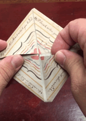Curator John Overholt demonstrates the folding a facsimile of the puzzle purse