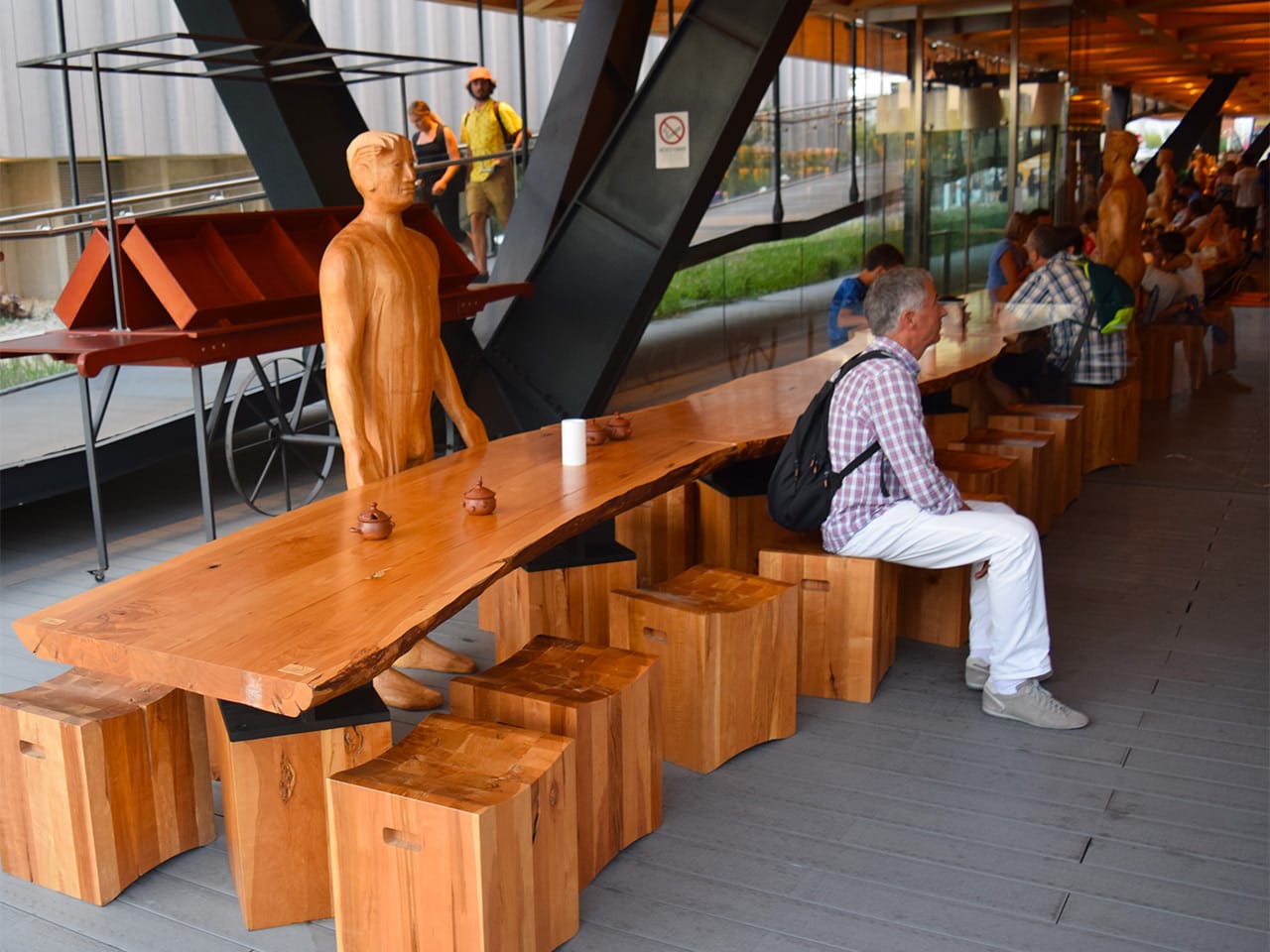 A wooden table lined with life-size wooden figures in the Chilean pavilion's restaurant