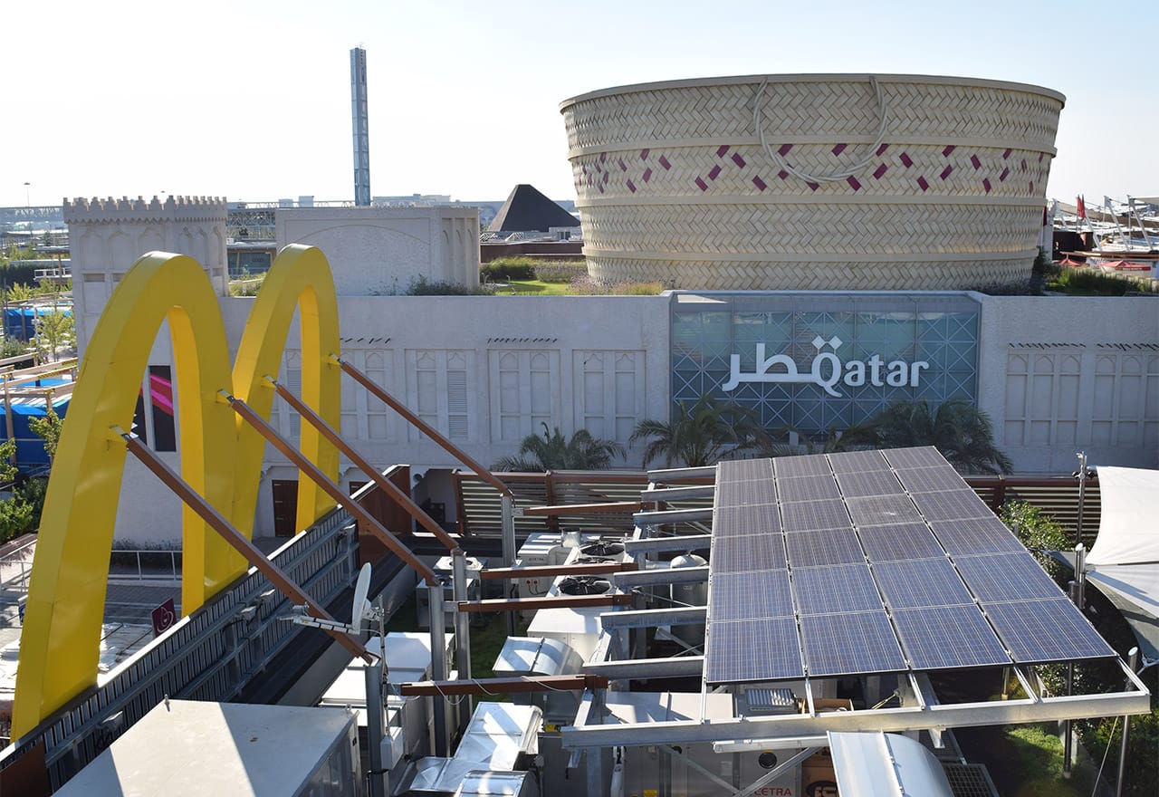 The breadbasket-shaped Qatari pavilion with Expo Milano's on-site McDonald's branch — with solar panels and a garden on its roof — in the foreground