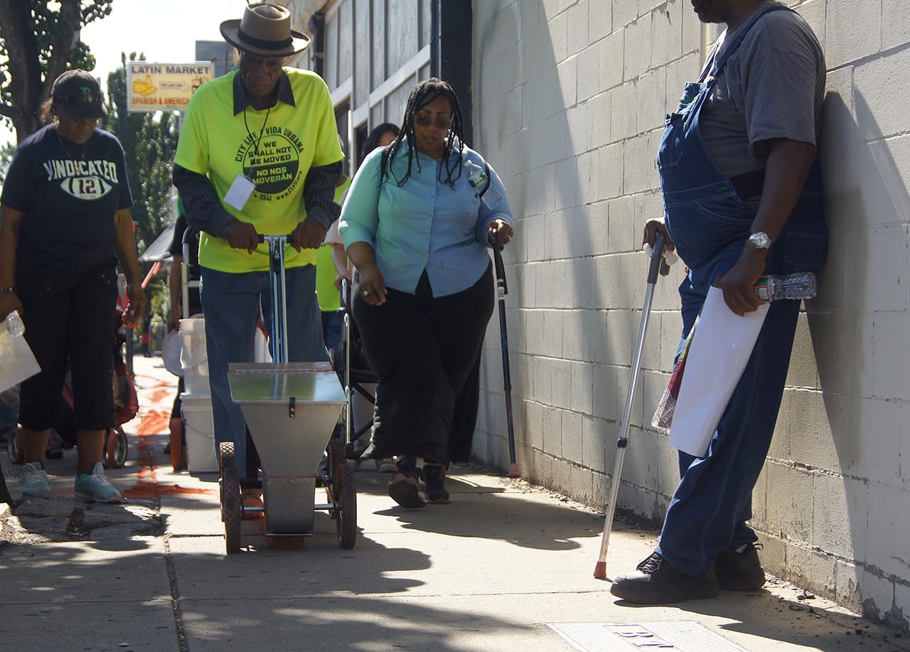 Heather Gordon, Mr. Marshal, and Carolyn Lomax push the chalker tool along Washington Corridor.