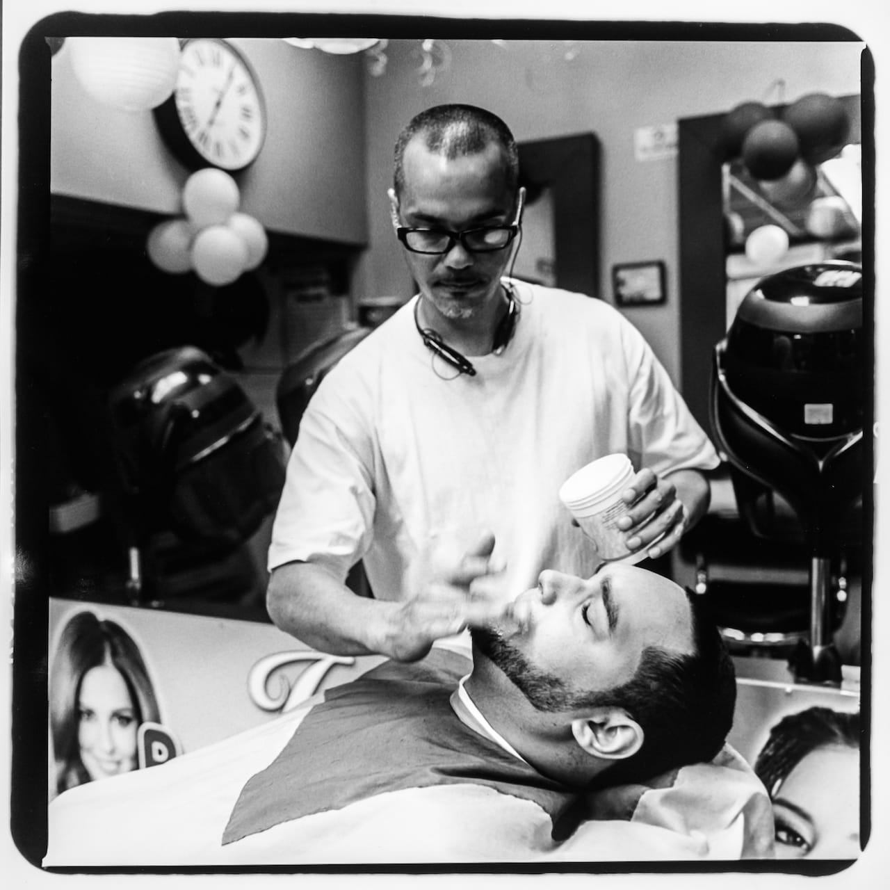 Tony Ramos giving one of his customers a haircut in a barber shop located at 1476 Jerome Avenue. Tony lives and grew up in the neighborhood where he works, been working at the shop for the past 3 years. Photo taken August 2015 by Berthland Tekyi-Berto/Bronx Photo League. 