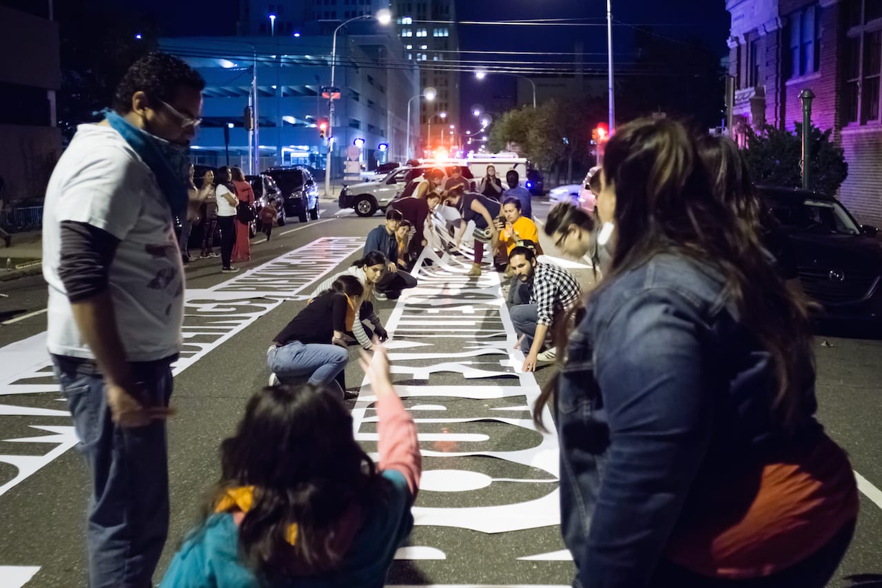 Volunteers and community members from Juntos help place "Somos Seres Humanos (We Are Human Beings)" on October 12 (photo by Jose Mazareigos)