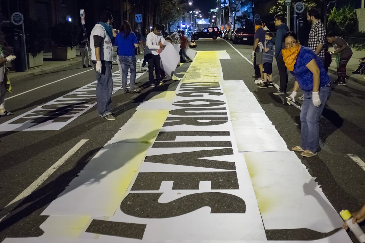 Volunteers and community members from Juntos help place "Somos Seres Humanos (We Are Human Beings)" on October 12 (photo by Jose Mazareigos)