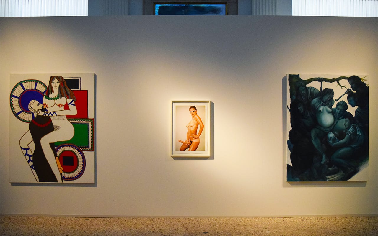 Installation view with, from left to right, Dorothy Iannone's "Suck my breasts I am your most beautiful mother" (1970–71), Lynda Benglis's "Lynda Benglis Advertisement in Artforum, November 1974" (1974), and Nicole Eisenman's "Hanging Birth" (1993)