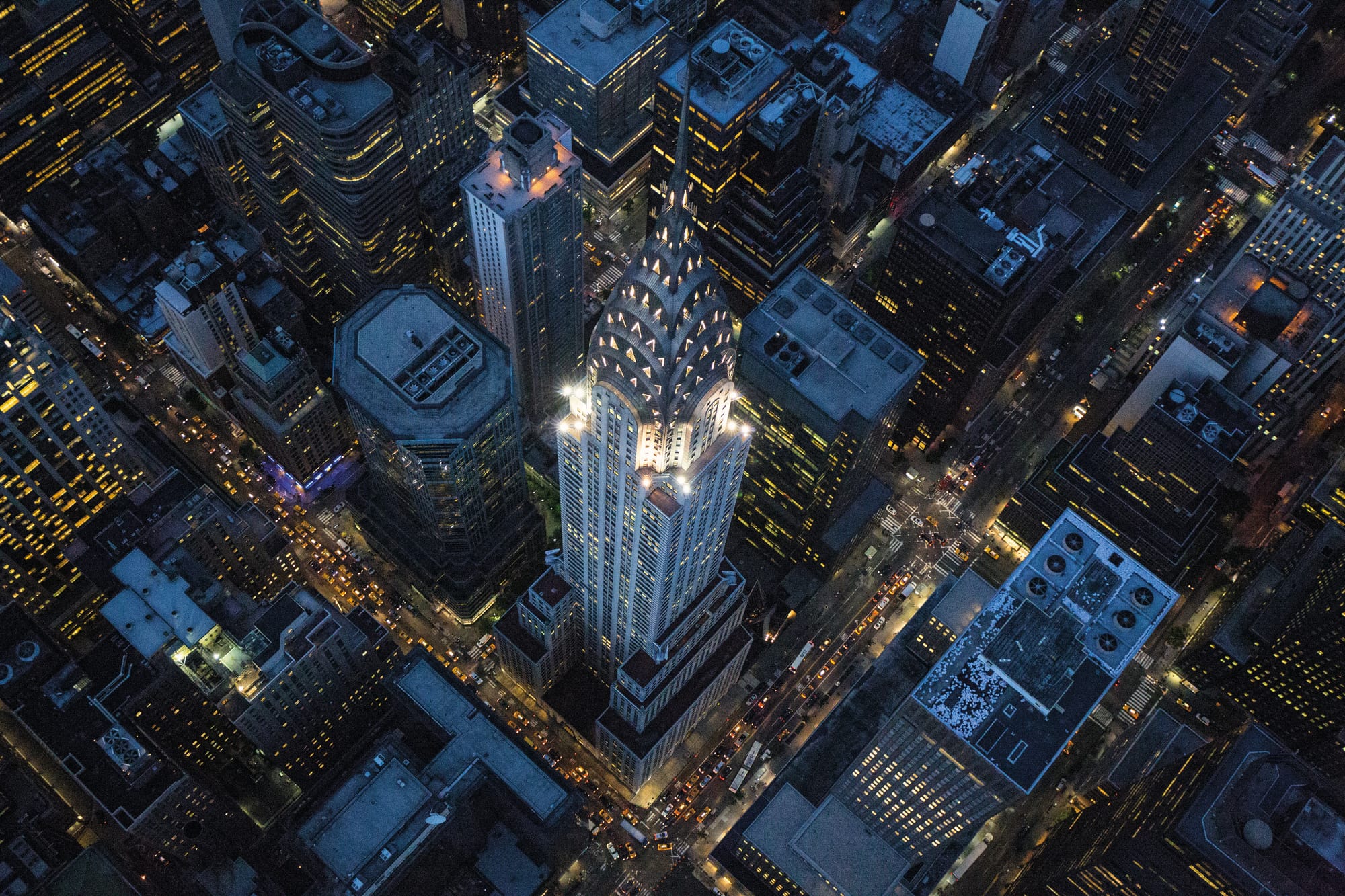The Chrysler Bulilding on an early summer evening in New York City. The design is fabricated from chrome-nickle steel and symbolizes the twentieth century. The Chrysler Building had sheet-metal shops on the 65th and 67th floors and the design motif is points radiating out from a rounded base, a sunburst to greet the world. William Van Alen‚Äôs seventy-seven story Chrysler Building was the world‚Äôs tallest for only eleven months, until the Empire State Building surpassed it in 1931, but no skyscraper has ever surpassed its harmonious design, the grace with which its crown emerges from its shaft, the seamless transition from brick to steel. The Chrysler Building owes its existence to Walter P. Chrysler, who backed Van Alen‚Äôs dazzling plan with his own cash after the original developer got cold feet. An industry study in 1929, just before the Crash, argued that construction costs rendered Midtown buildings above sixty-three stories unprofitable ventures, and the top seven floors of the Chrysler Building are barely rentable thanks to that gorgeous crown. Chrysler was paying for immortality, but he made Van Alen sue for his fee.