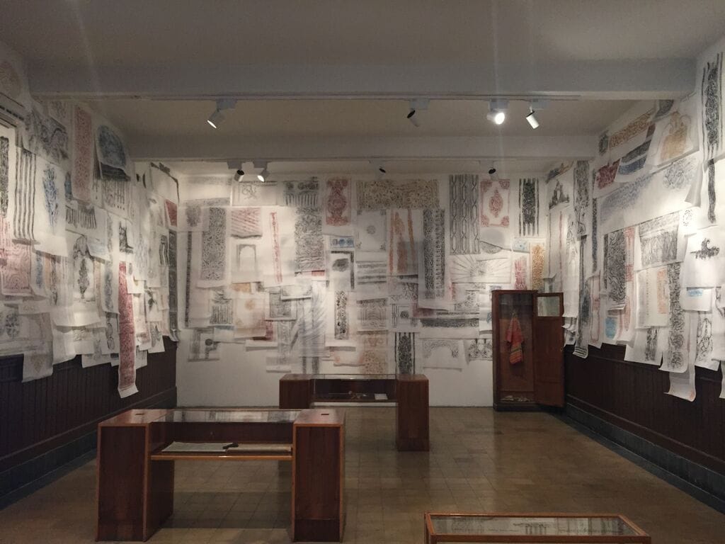 Hallway with glass-and-wood cases and architectural rubbings in Michael Rakowitz, "The Flesh is Yours, The Bones are Ours" at Galata Greek Primary School (click to enlarge)